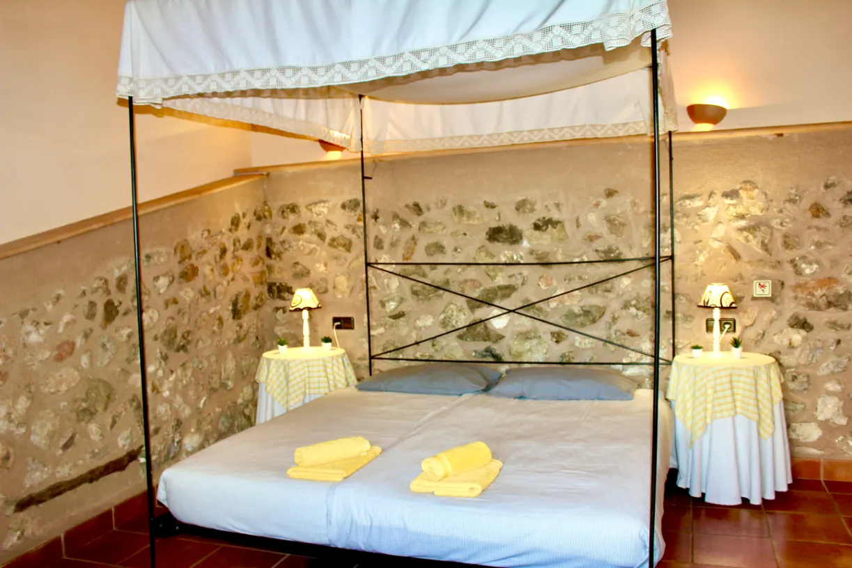 Dormitorio principal con cama de dosel y pared de piedra